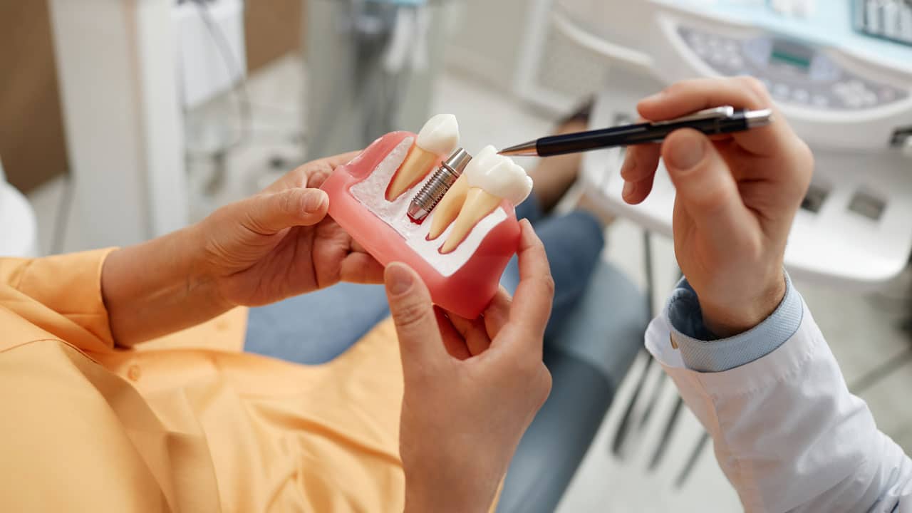 Dentist showing patient model of dental implant
