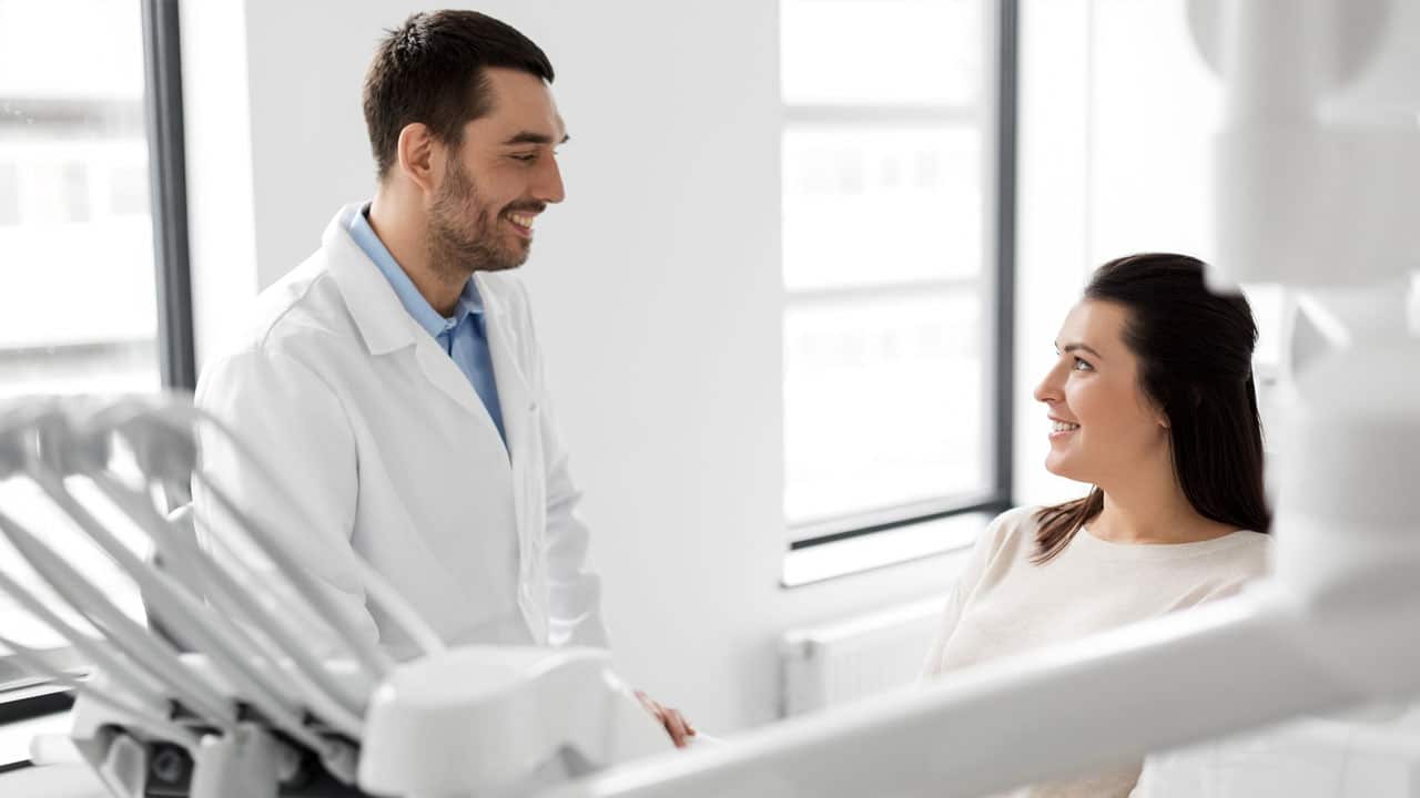 Dentist talking with female dental patient in chair